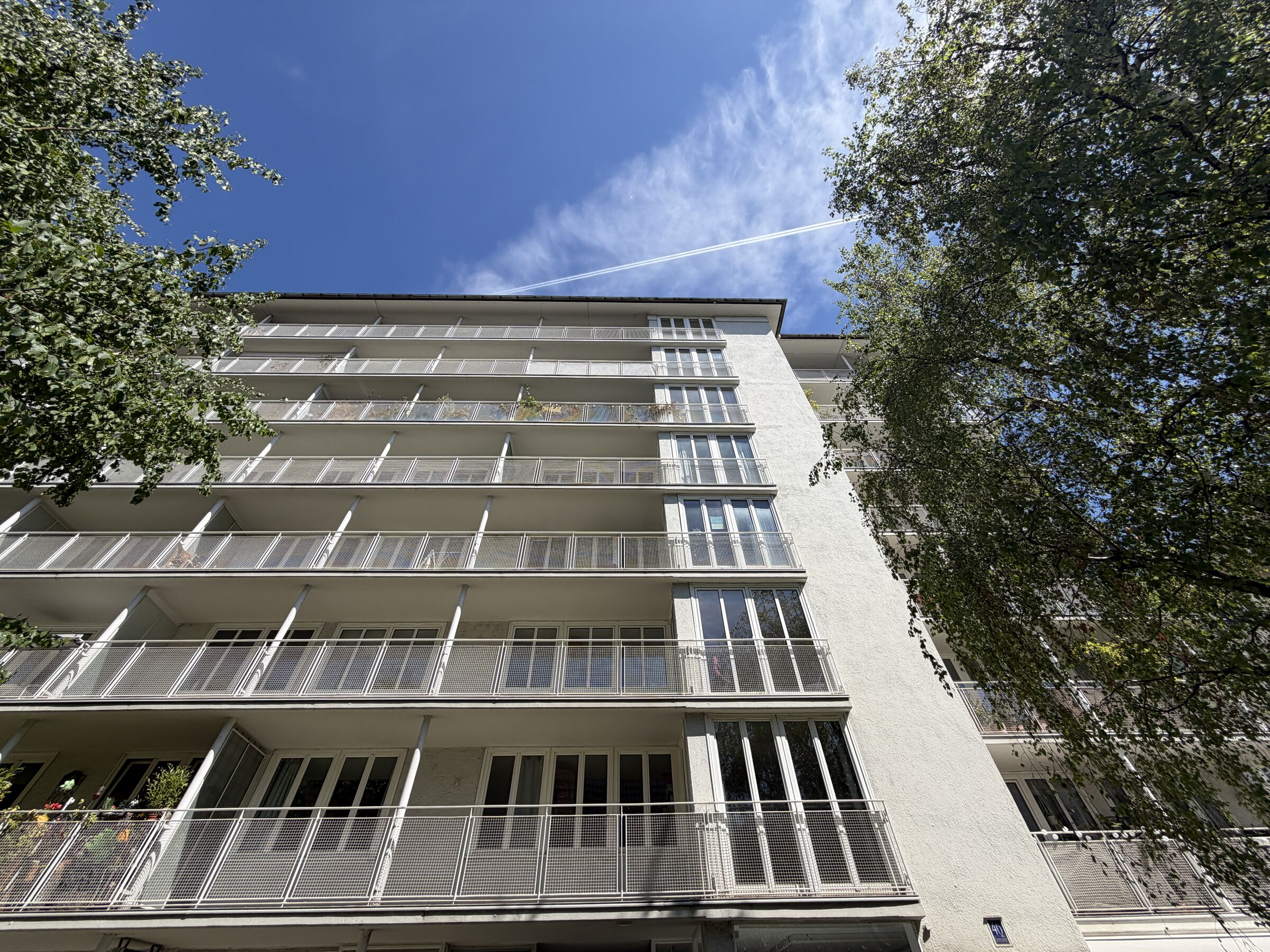 Blick von unten an der Südfassade entlang: Balkone, Stützen, raumhohe Fenster